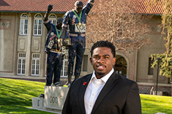 圣何塞州立大学校园里，身穿西装的黑人男子站在胜利雕像前